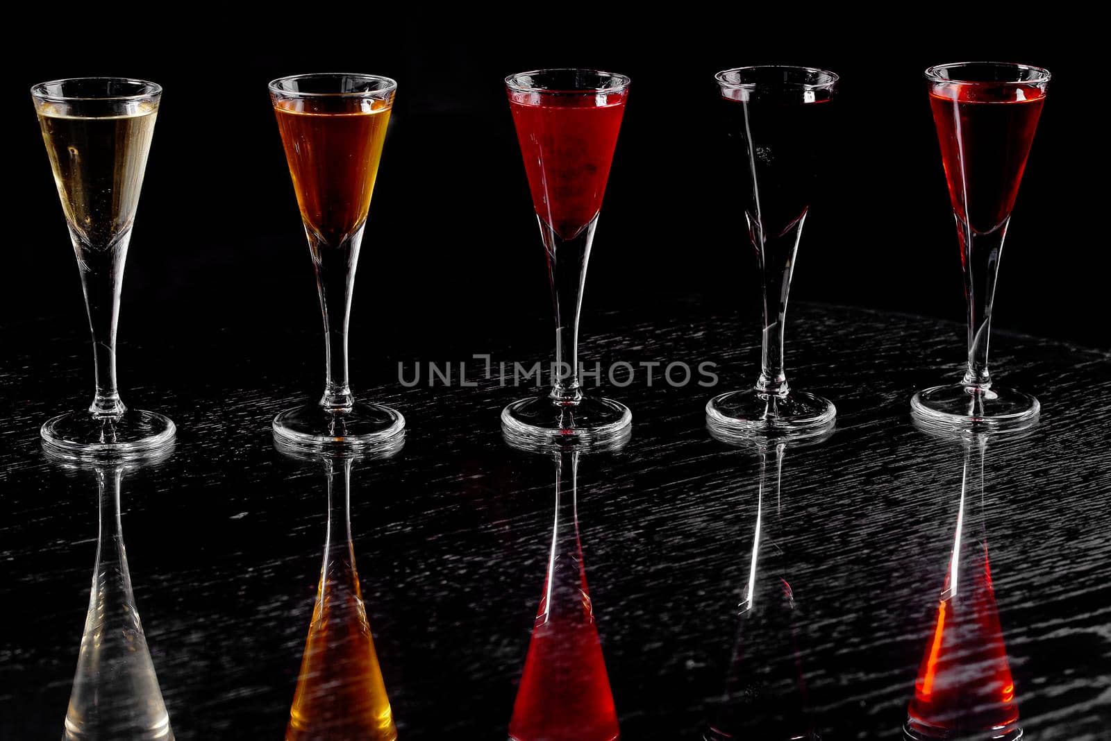 five shots on a mirrored table on a black counter stand-up . High quality photo