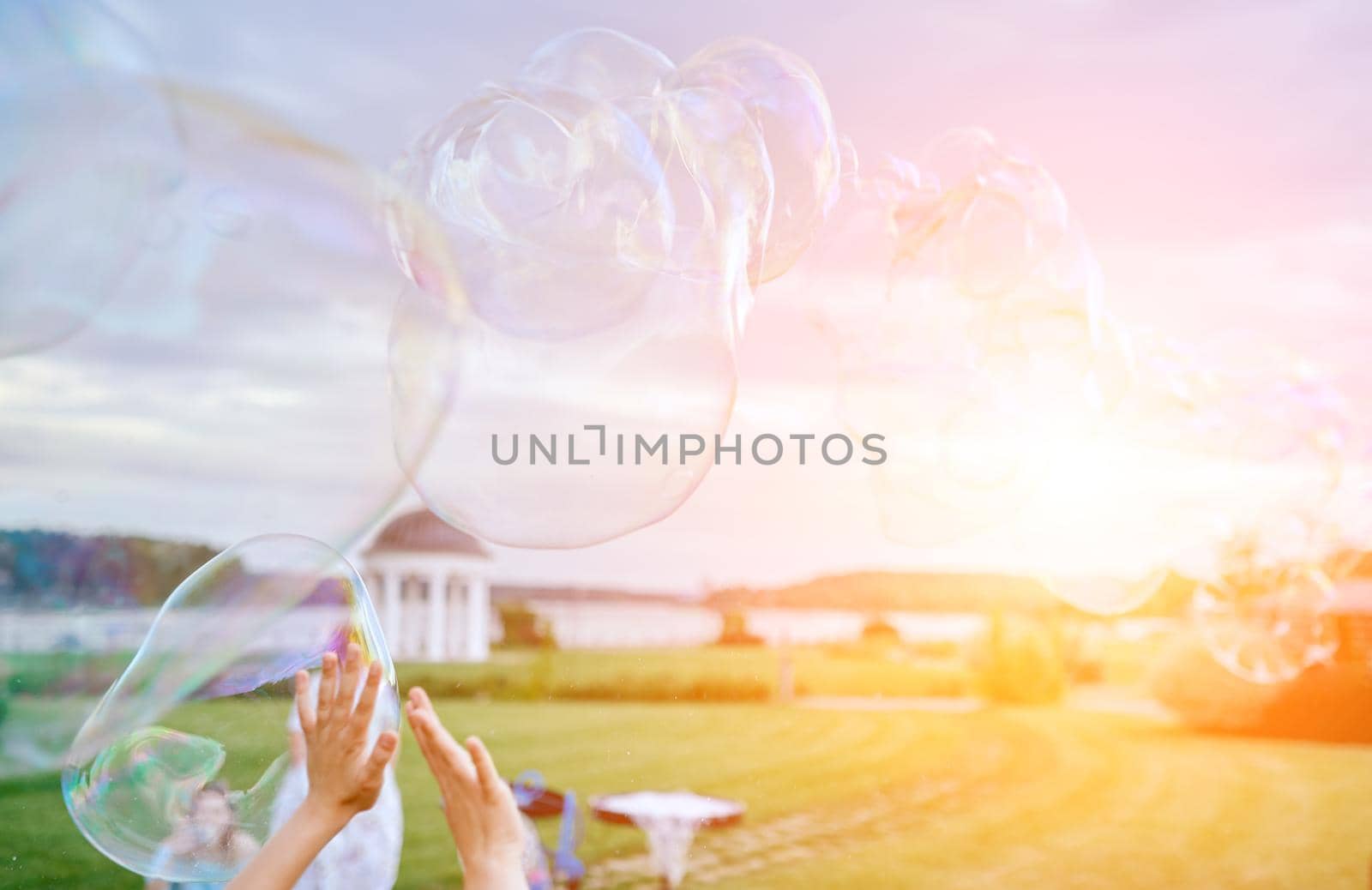 hands stretch to very large soap bubbles against the backdrop of nature . High quality photo