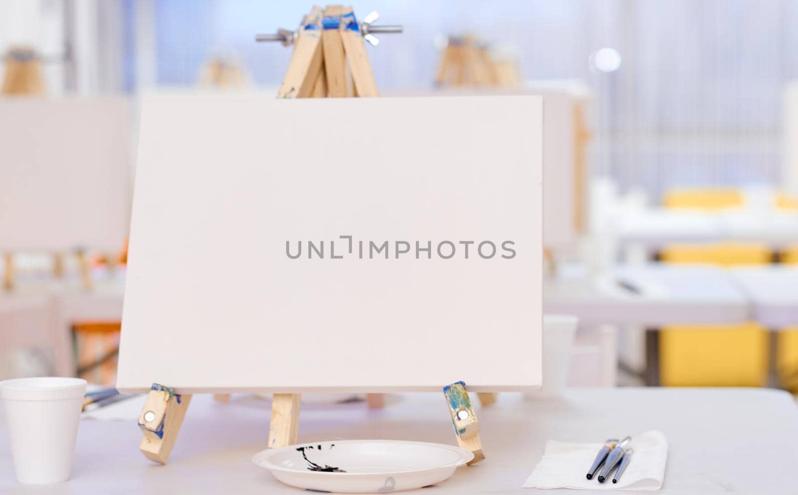 On the table brushes on a napkin, a plate in the form of a palette and easel . High quality photo