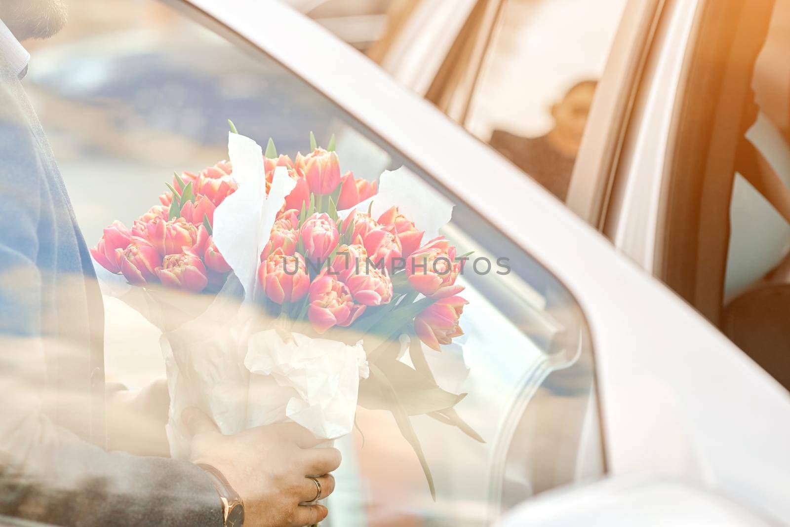 Handsome groom come in car with bouquet. Elegance person. High quality photo