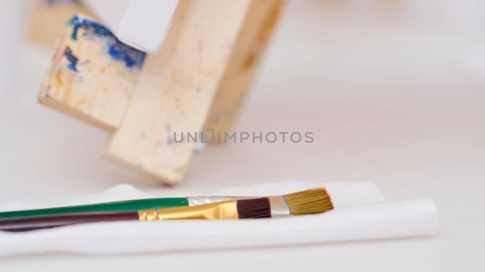 three brushes on a napkin lie on the table near the easel filmed close. High quality photo