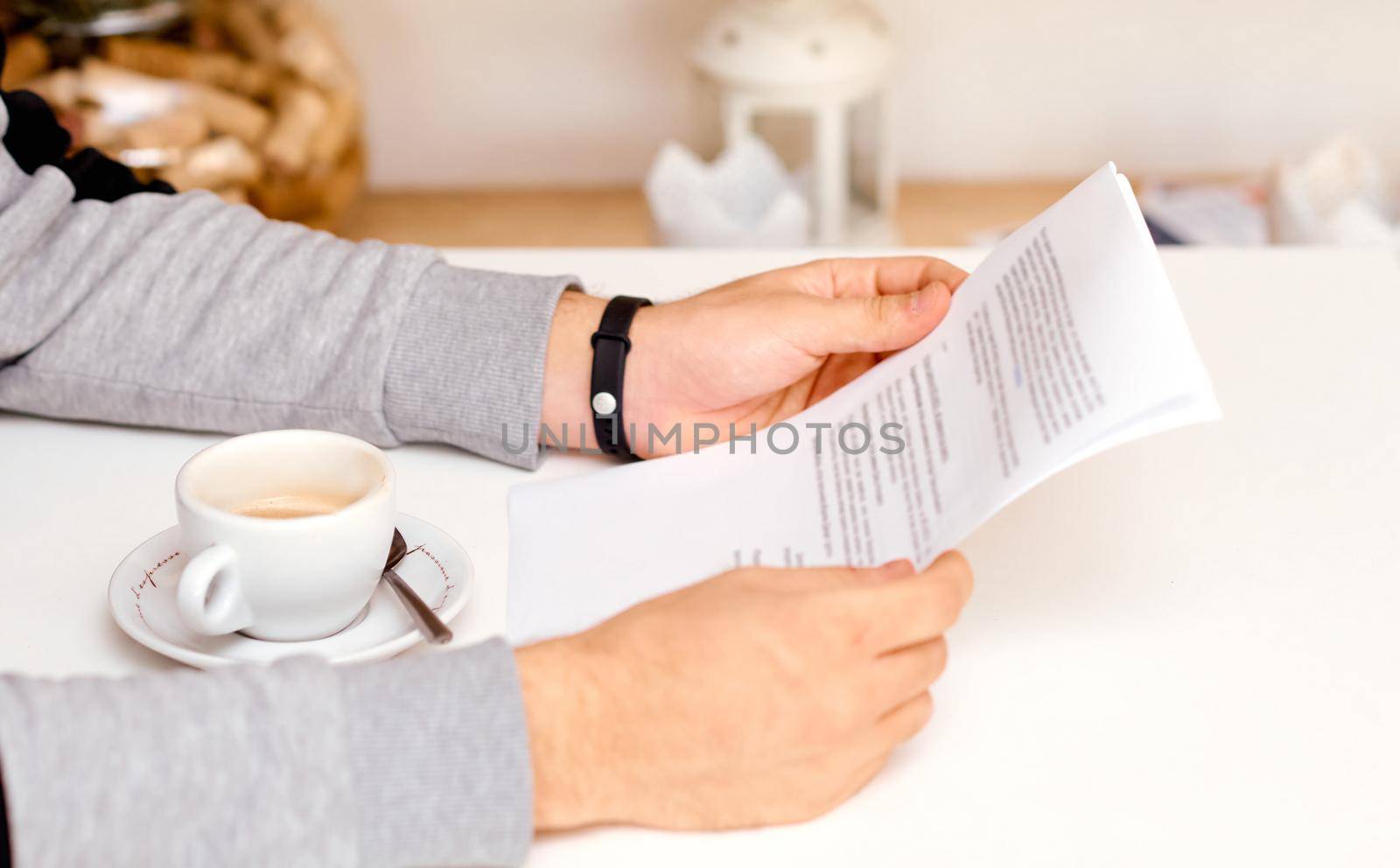 the man holds with both hands and reads the document on sheets of paper with coffee between his hands. High quality photo