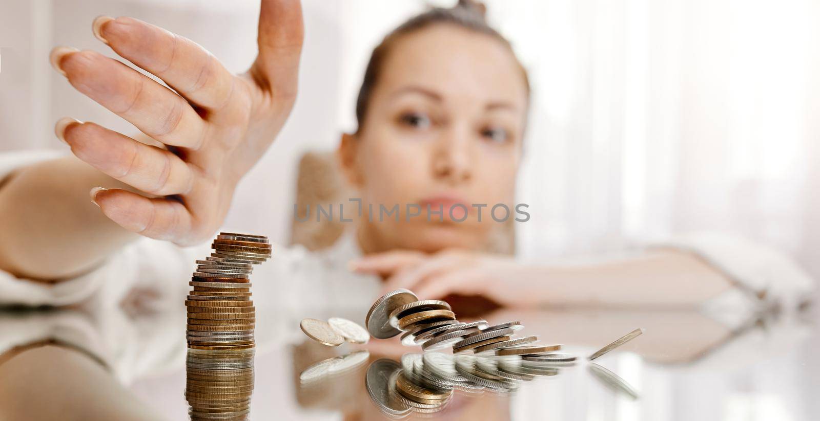 A woman destroys a stack of coins from the tower. Concept. Filmed in motion. Dynamics. High quality photo