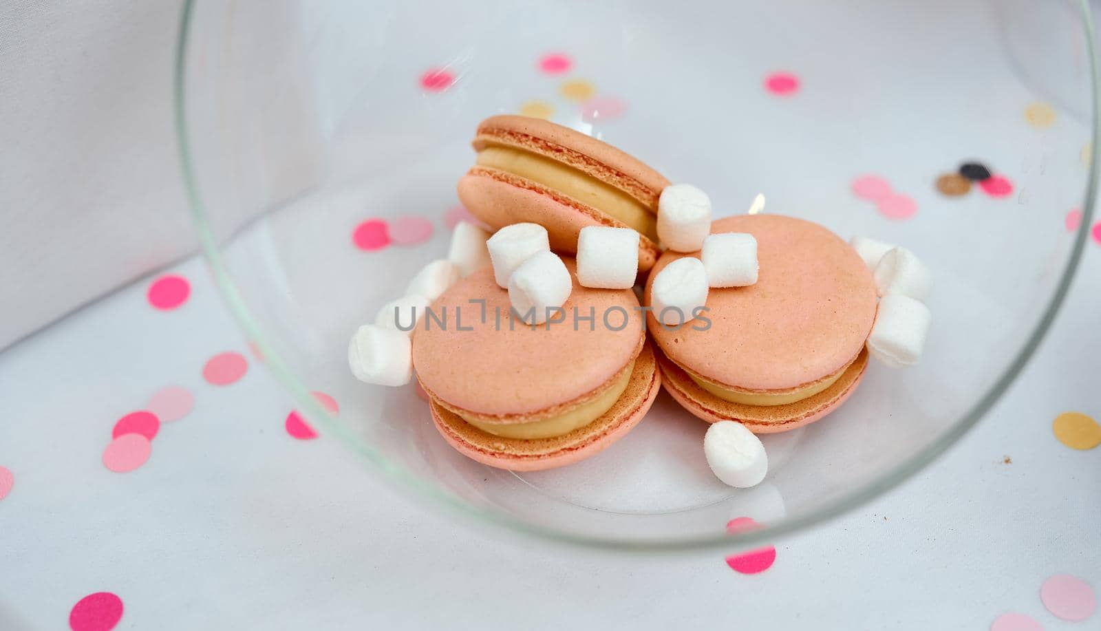 Colorful peach Macaroons with white marshmallows In A Glass Vase On White Table. High quality photo