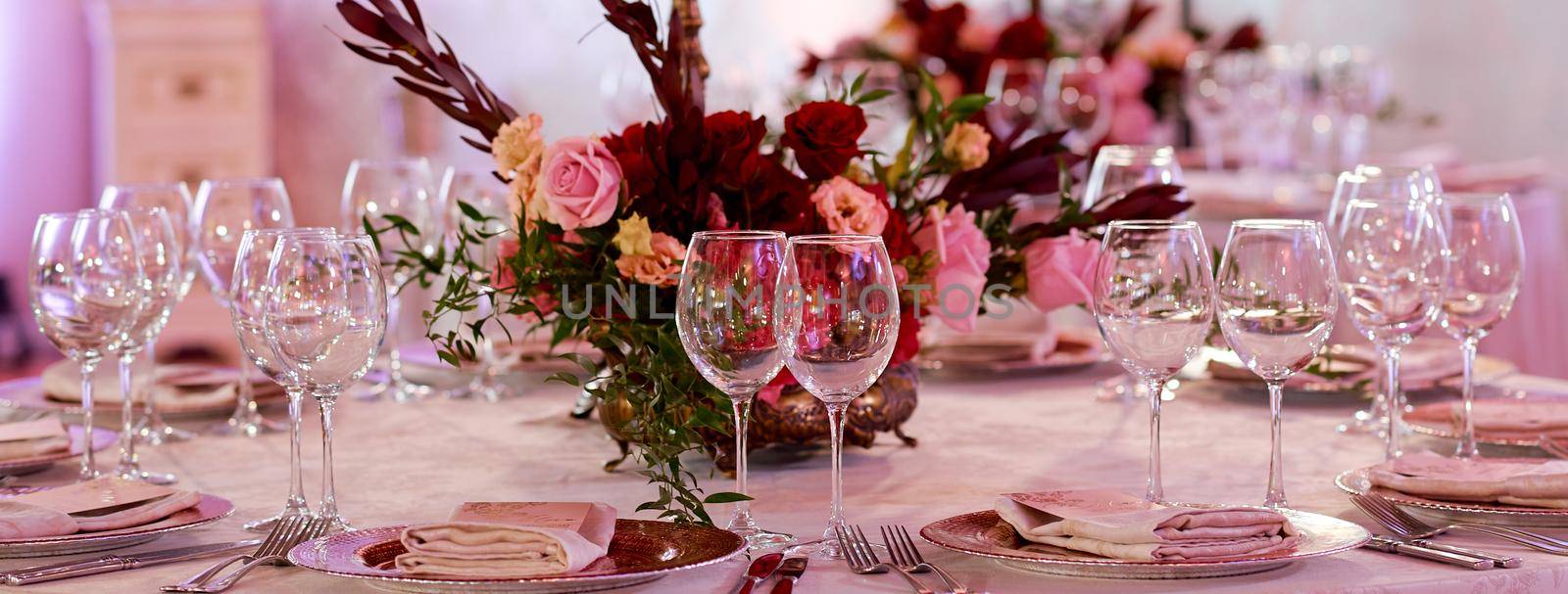 A dining table filled with wine glasses served for guests. Table with flowers in the middle. High quality photo