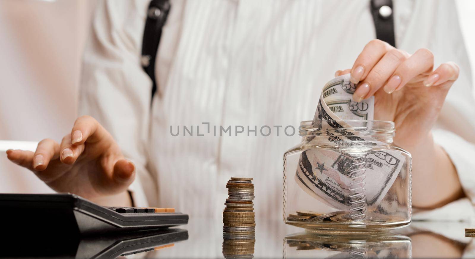 The woman counts the money and puts it in a glass jar on the mirrored table. High quality photo