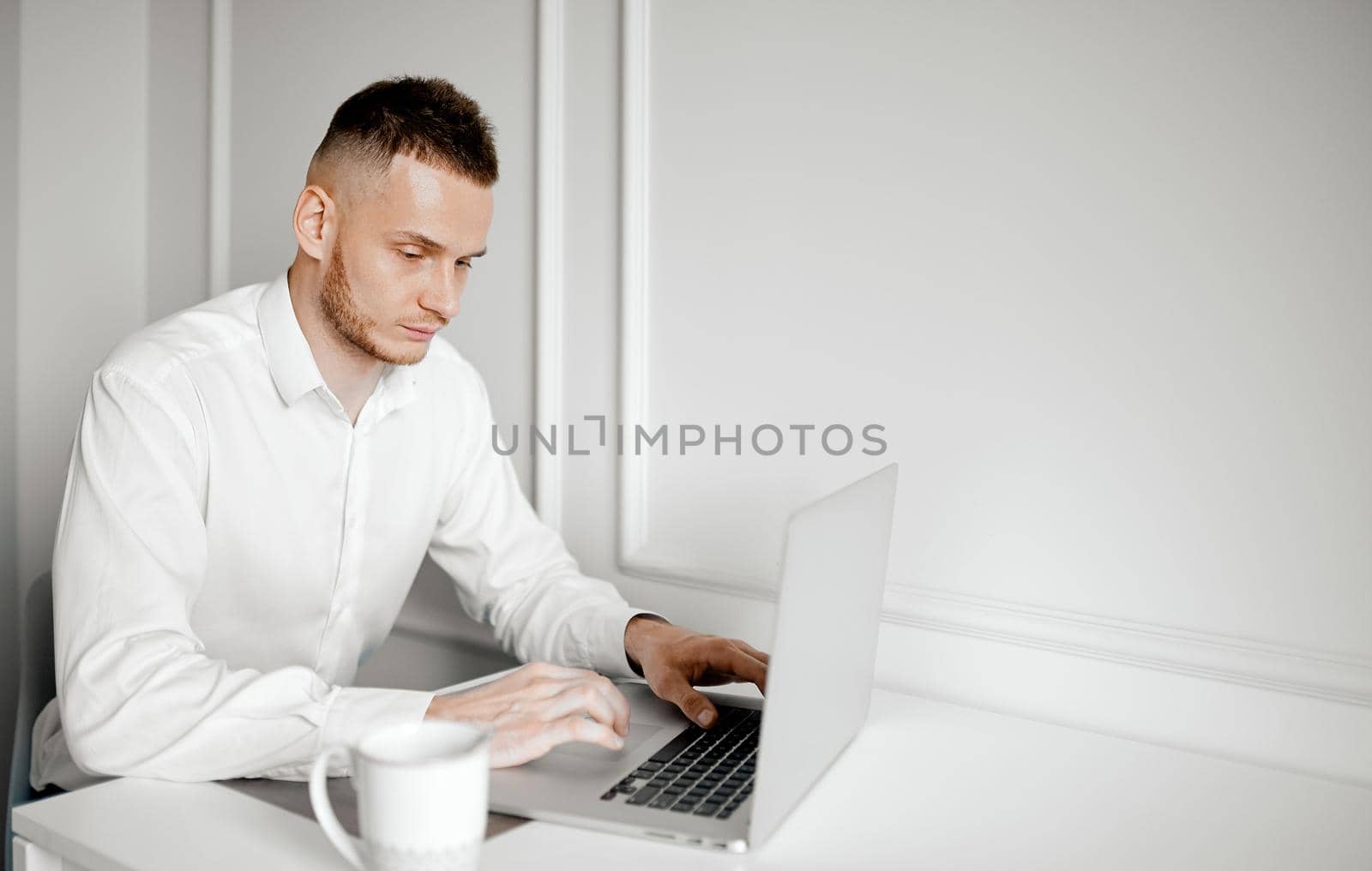 A young businessman works at a table with a cup of coffee and a laptop. High quality photo