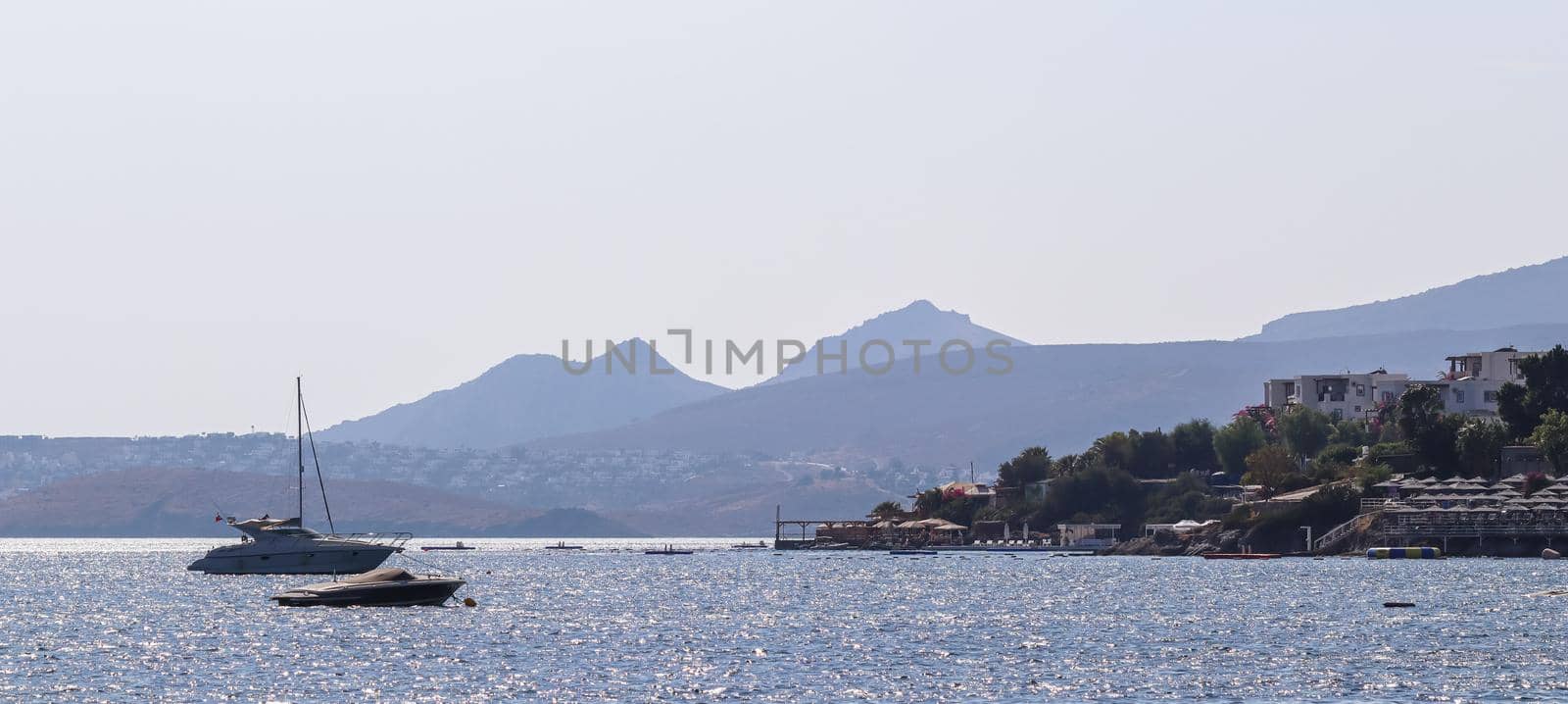 Blue sea sparkling in the sun. Beautiful coast with islands, mountains and yachts. Summer holidays concept