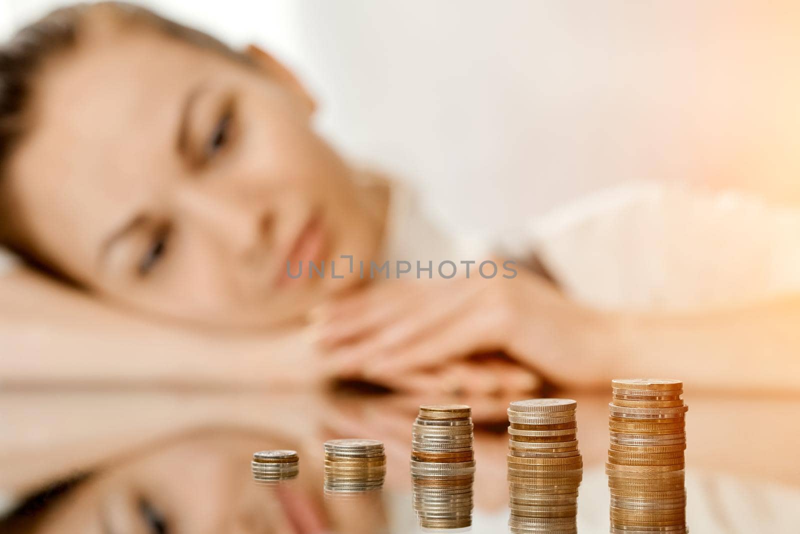 a woman looking thoughtfully at her savings in stacks of coins on the table. High quality photo