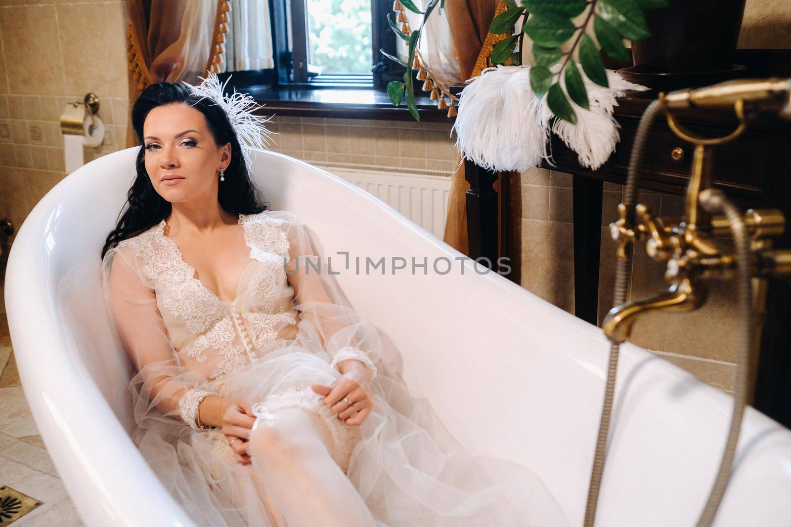 the bride, dressed in a boudoir transparent dress and underwear, lies in a vintage bathroom. Morning of the bride.