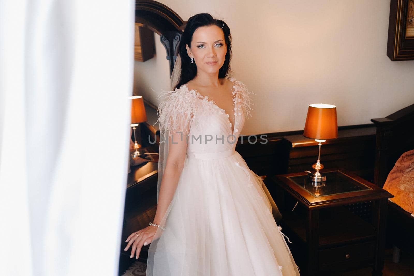 Portrait of the Bride in a wedding dress in the interior of the house near the mirror by Lobachad