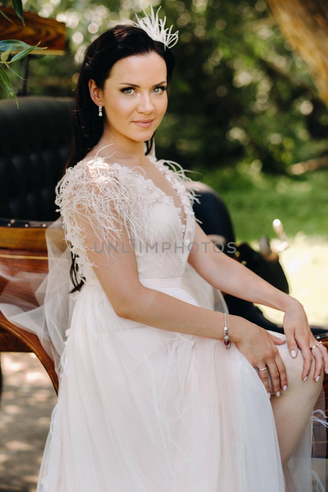 Stylish bride stands near the carriage in nature in retro style.