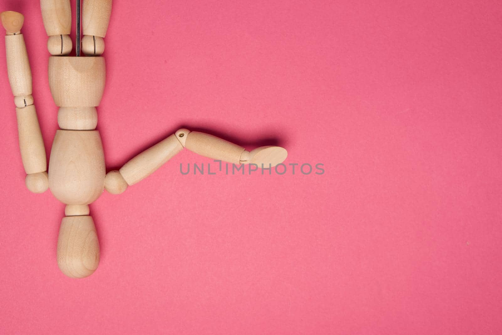 wooden mannequin on pink background posing close-up. High quality photo