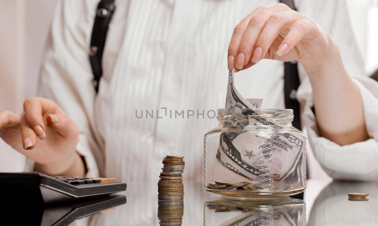 woman after counting on a classic calculator pulls a banknote from the jar. High quality photo