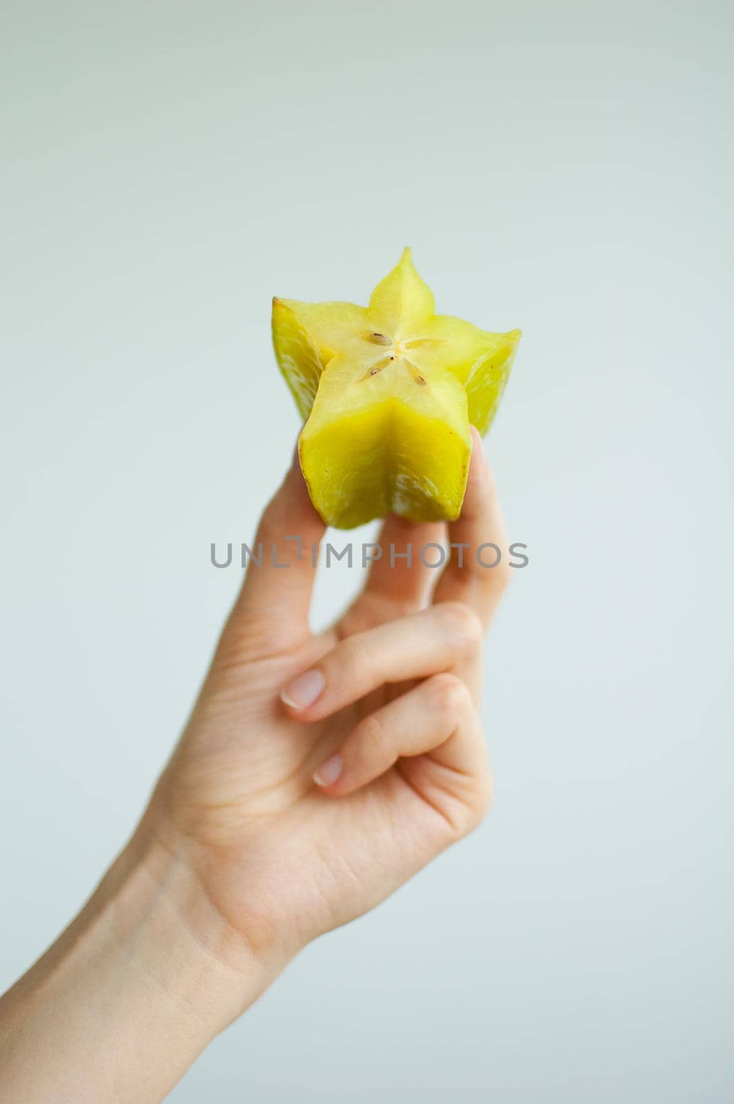 Female hands are holding slice of exotic ripe starfruit or averrhoa carambola. Healthy food, fresh organic star apple fruit.