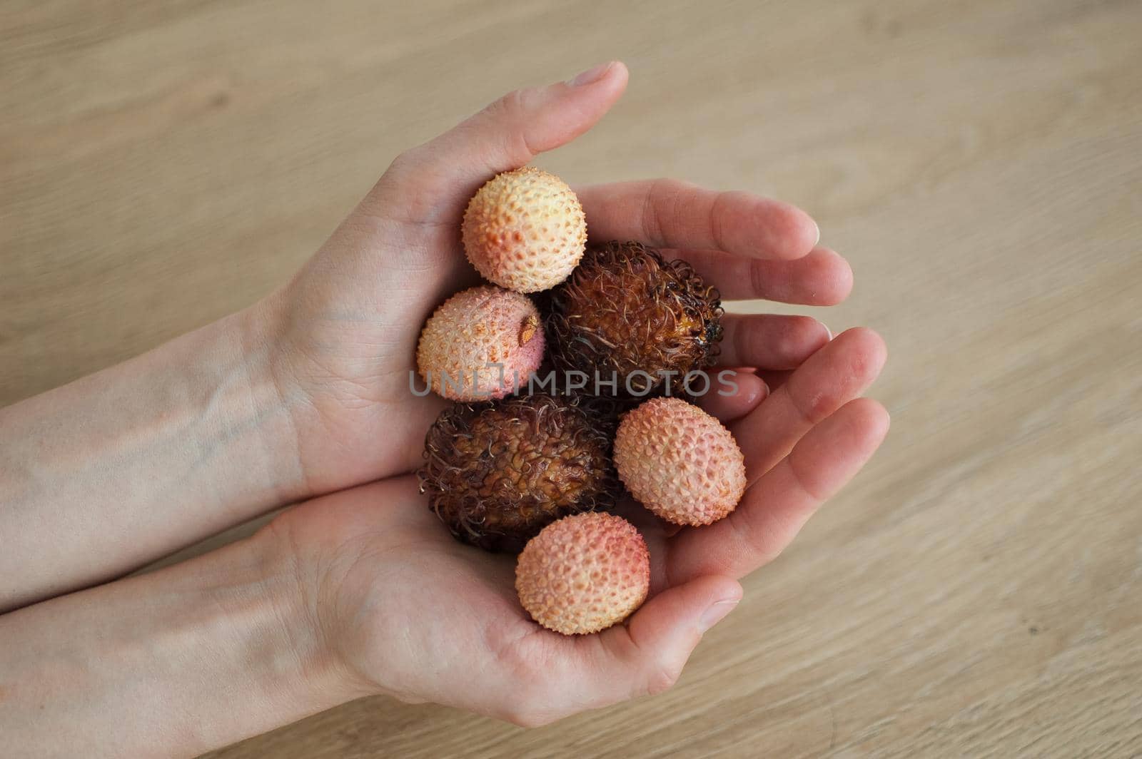 Female hands are holding exotic ripe rambutan and leechy or lychee fruits. Healthy food, fresh organic fruit. by balinska_lv