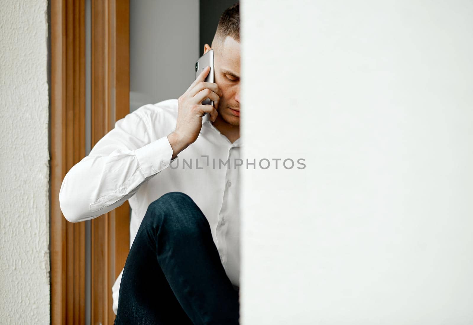 A man is talking on the phone at home sitting on a pallet. removed from the street. High quality photo