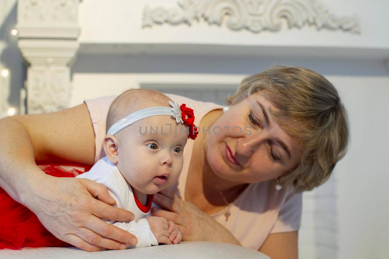 The grandmother looks at the newborn girl with love. An elderly woman and a three-month-old girl.