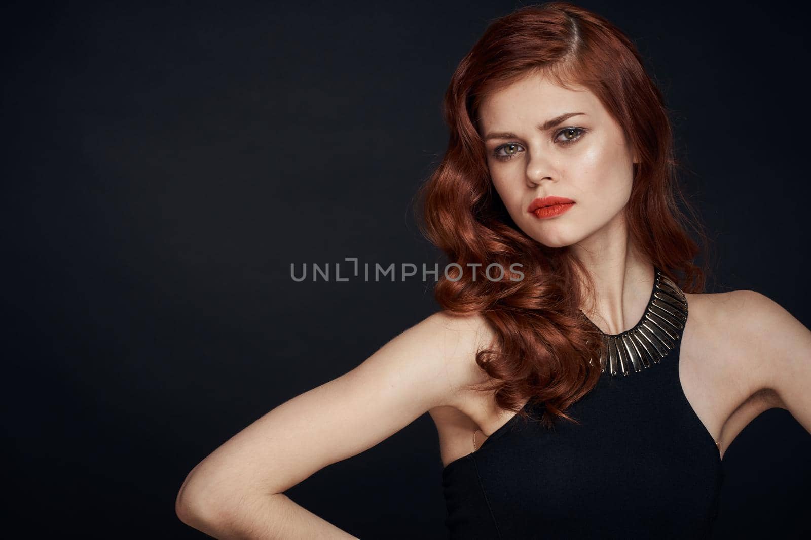 attractive red-haired woman in a black dress hairstyle dark background. High quality photo