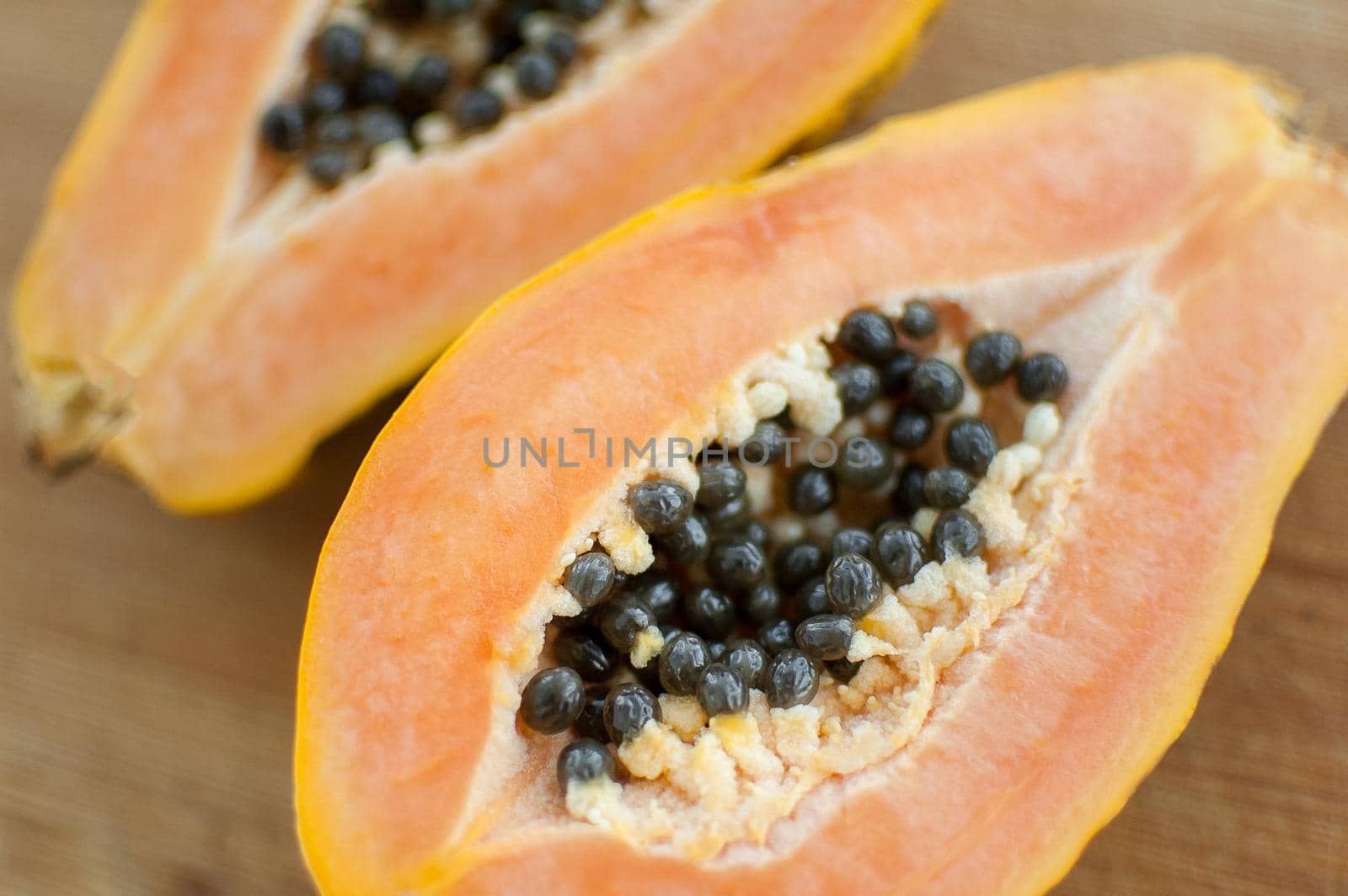 Fresh organic ripe papaya fruit cut in half on a wooden board. Exotic fruits, healthy eating concept by balinska_lv