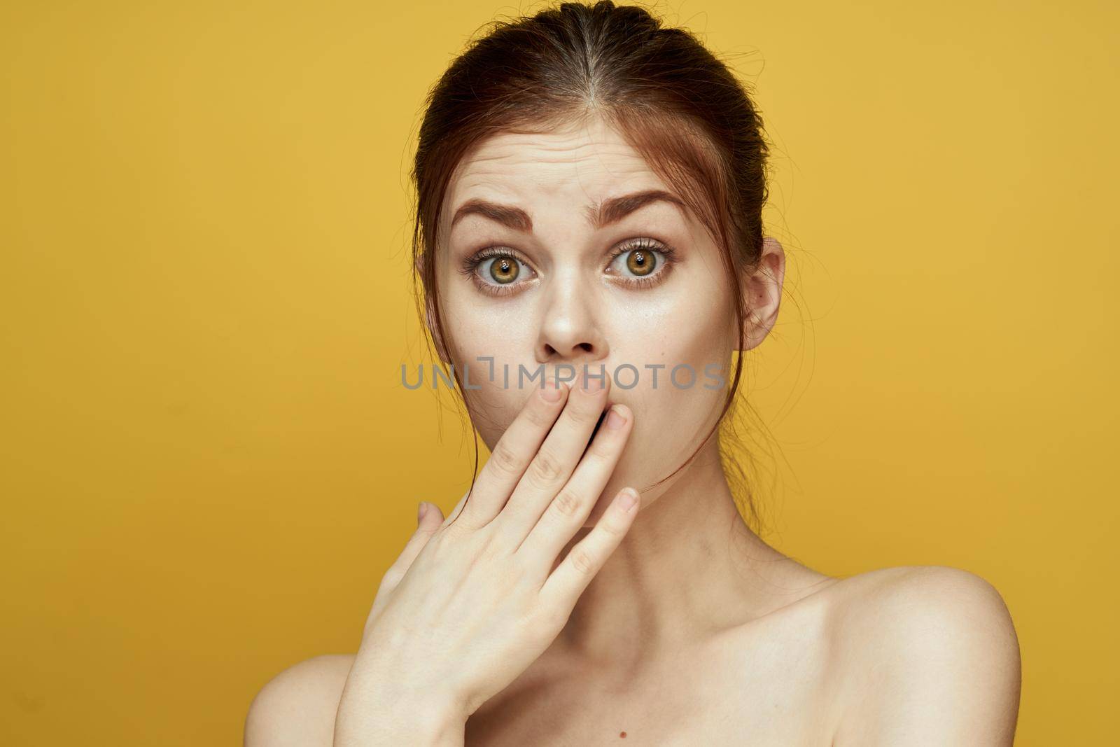 pretty woman naked shoulders and posing clear skin yellow background. High quality photo