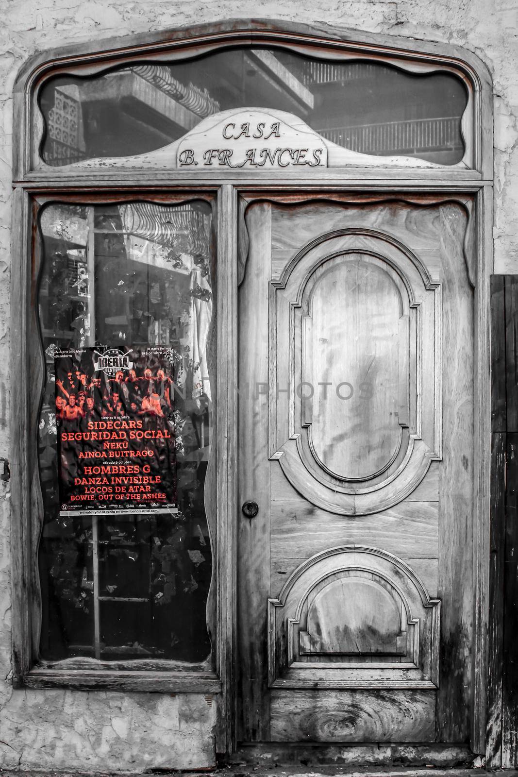 Benidorm, Alicante, Spain- October 9, 2021: Old wooden door next to concert poster on the glass