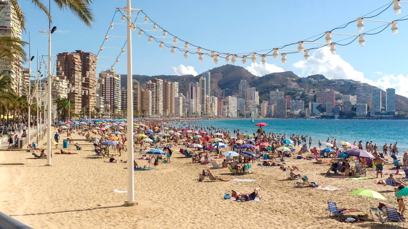 Benidorm, Alicante, Spain- October 9, 2021: People sunbathing on Levante beach on a Sunny day of Autumn in Benidorm