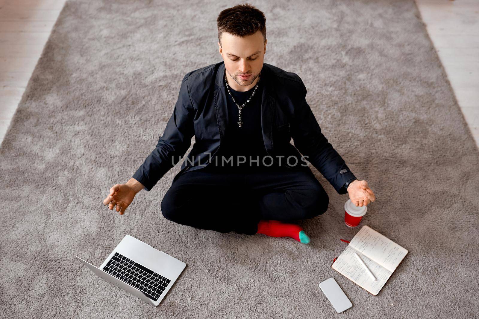 Reflective man with laptop sit in lotus on carper by AntonIlchanka