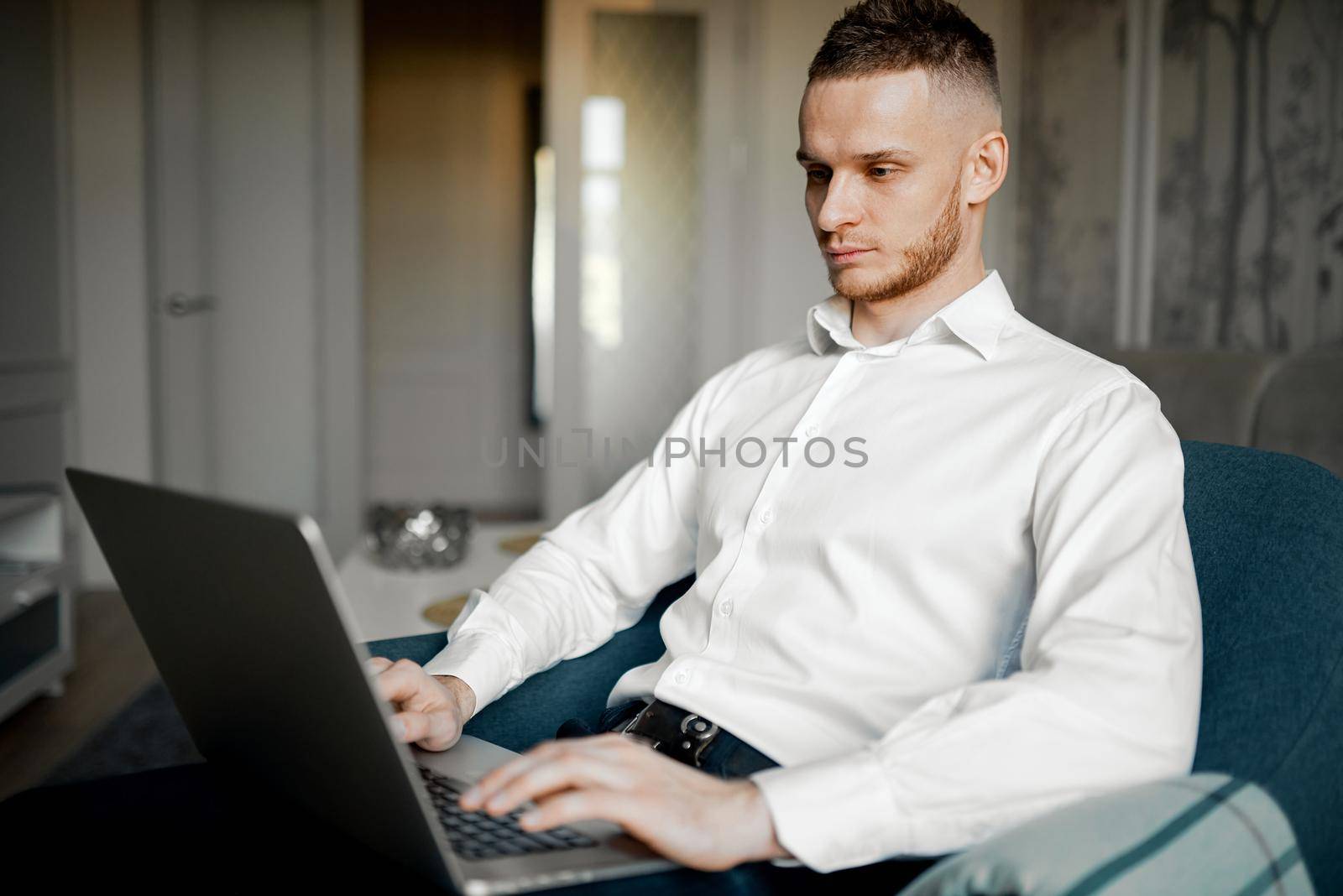 a young man works at a laptop on the couch at home. High quality photo