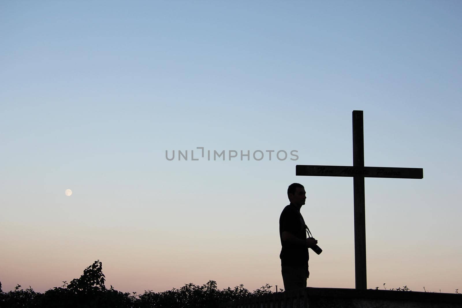 Silhouette of tourist takes photos with a cross on the foreground