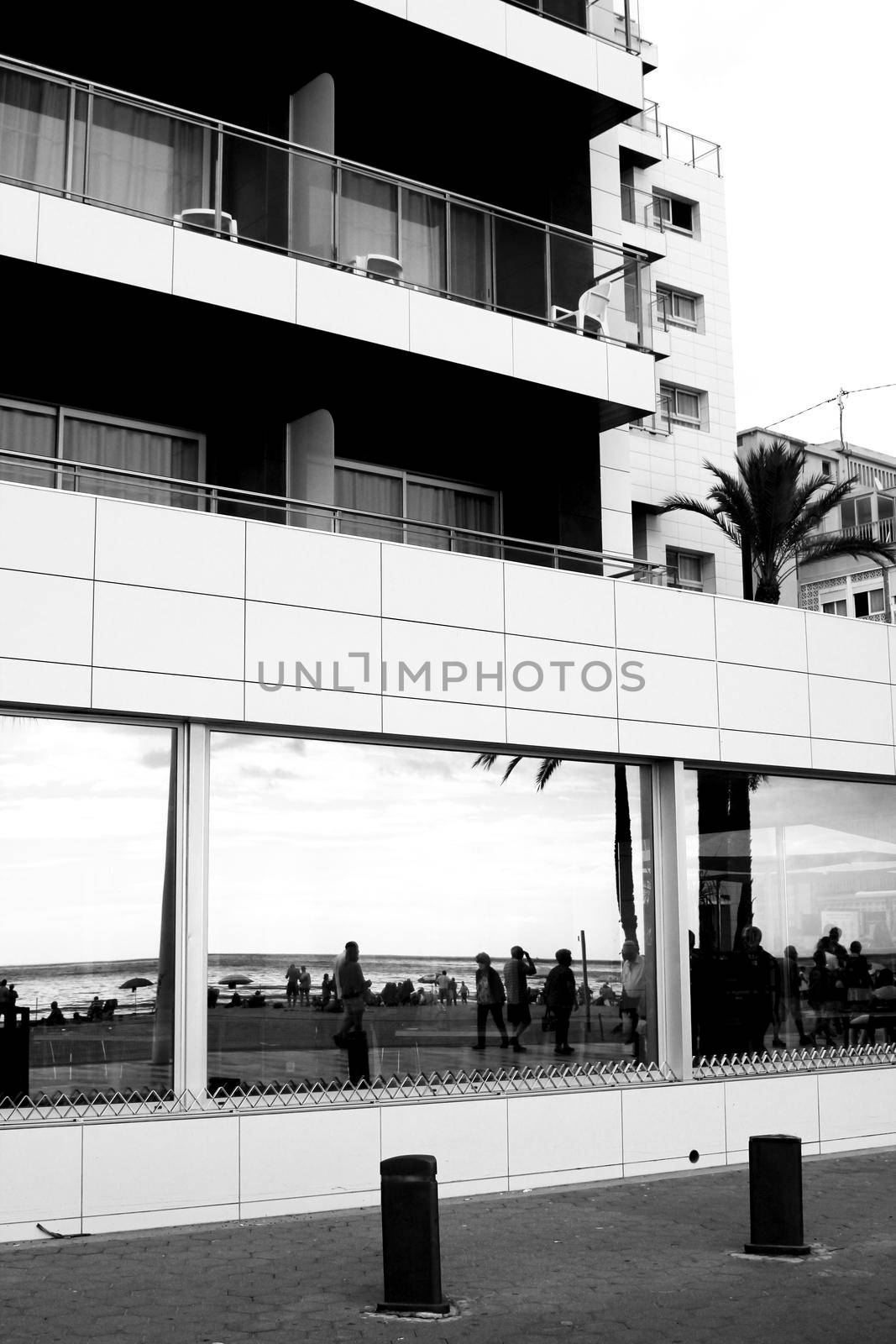 Benidorm, Alicante, Spain- October 9, 2021: Reflection on a glass of a building of people walking on a promenade of Benidorm