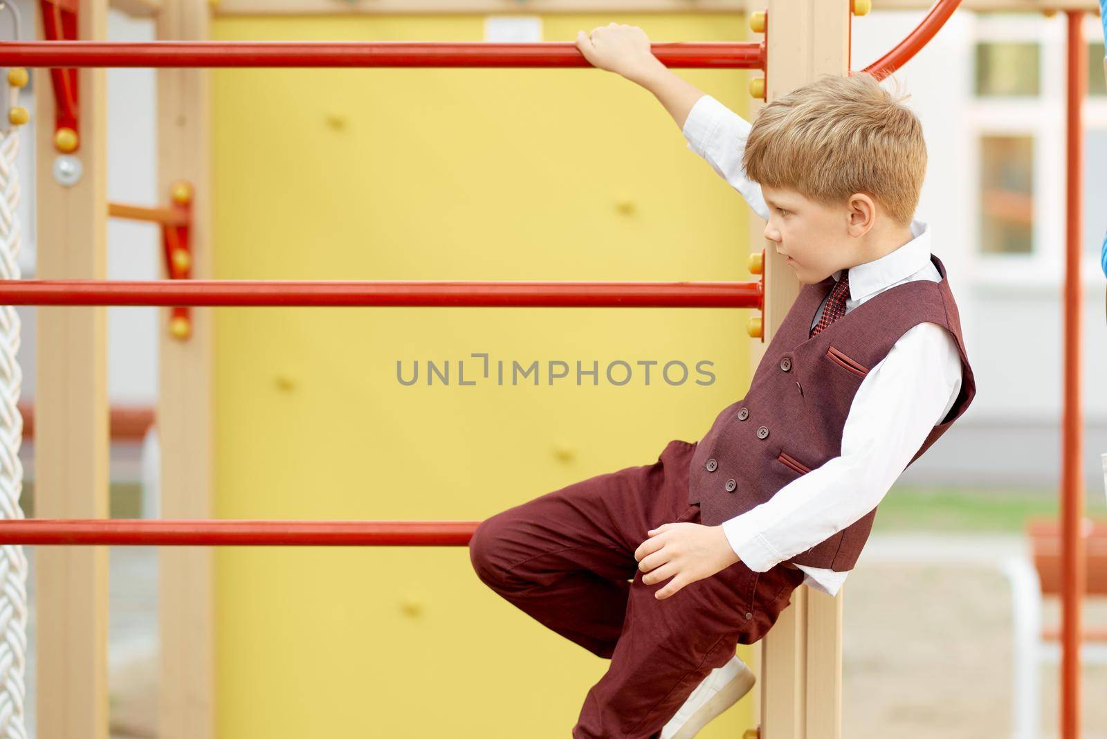 Boy in strict suit plays on the stairs at school on the first day by AntonIlchanka