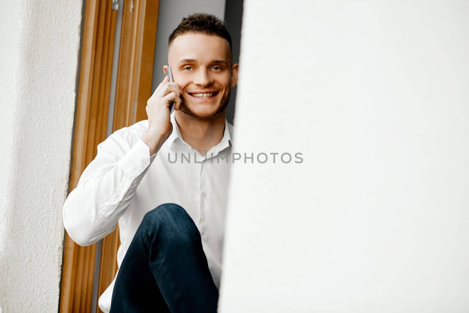 happy man sitting on the windowsill and talking on the phone. High quality photo