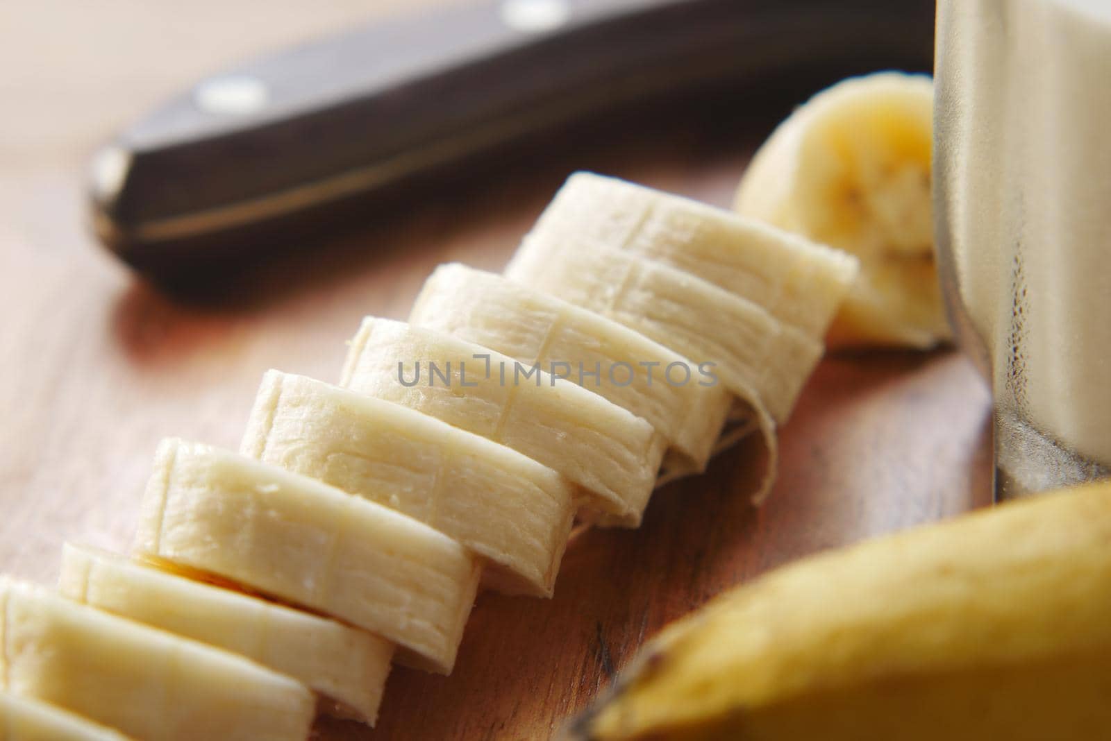 close up of slice of banana glass of milk on table .