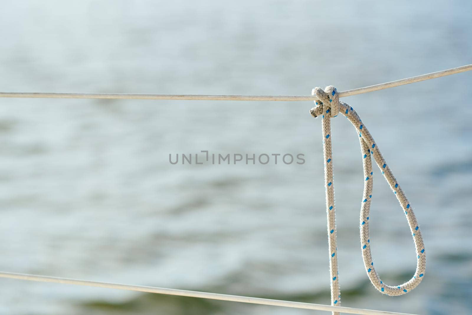 Knot on the fence of the yacht board against the background of the ocean sea water. High quality photo