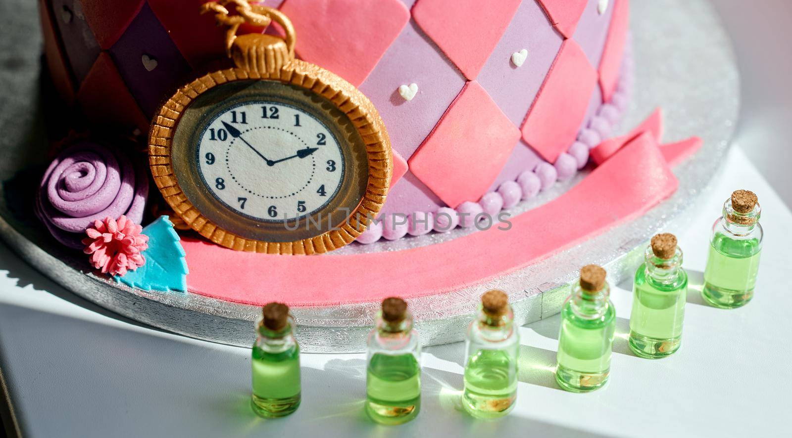 Stylized cake for the holiday in the style of Alice in Wonderland with jars with potion next to. High quality photo