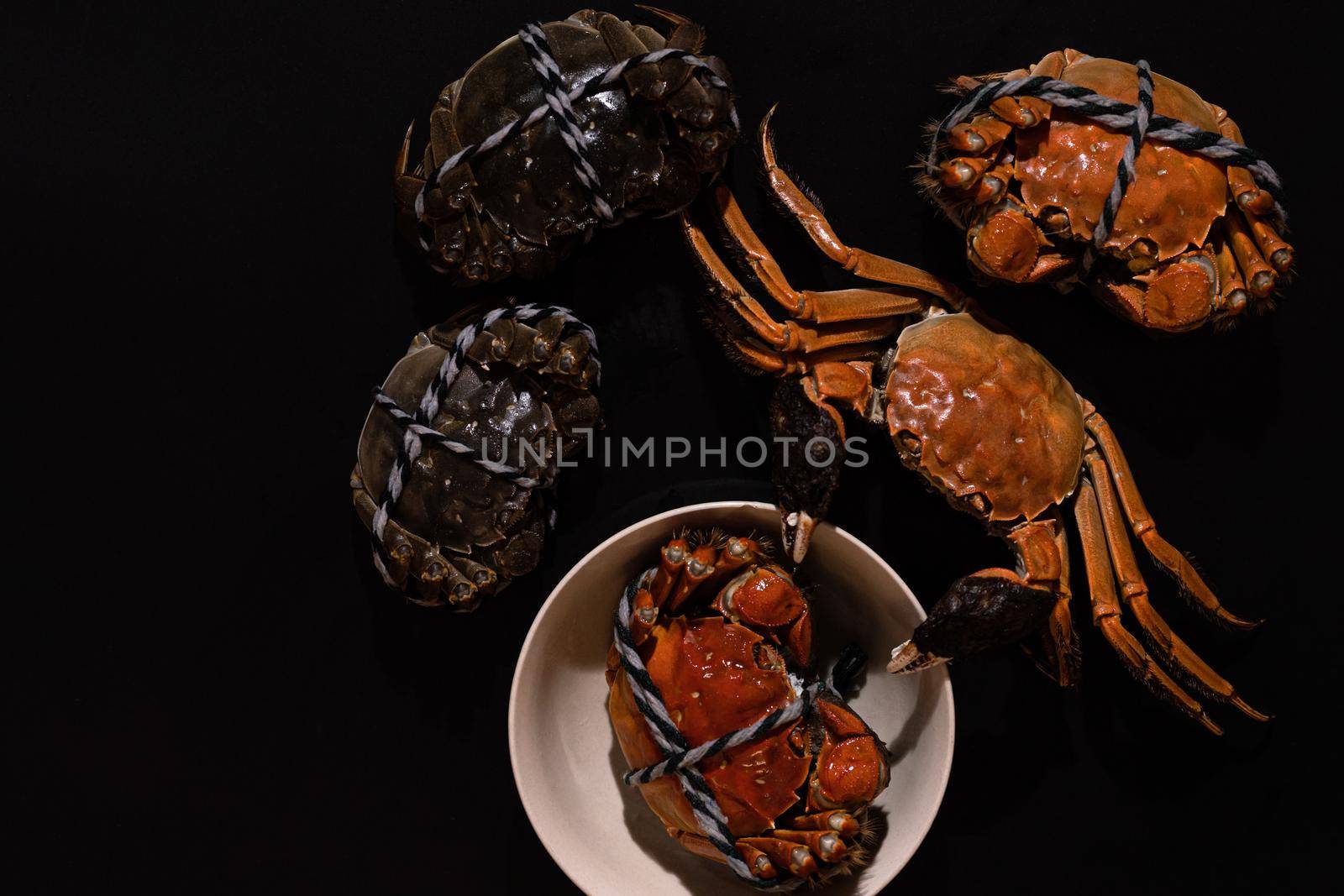 boiled Shanghai hairy crab or Chinese mitten crab (Eriocheir sinensis) with Chili and herb on black background by psodaz