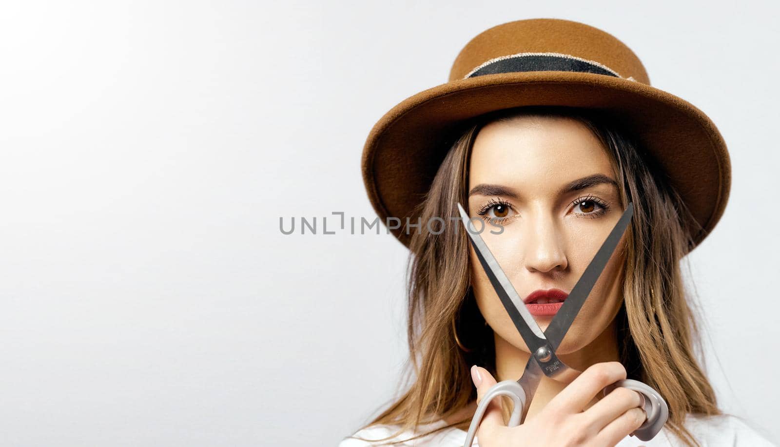 A woman wearing a hat looking through scissors hight quality