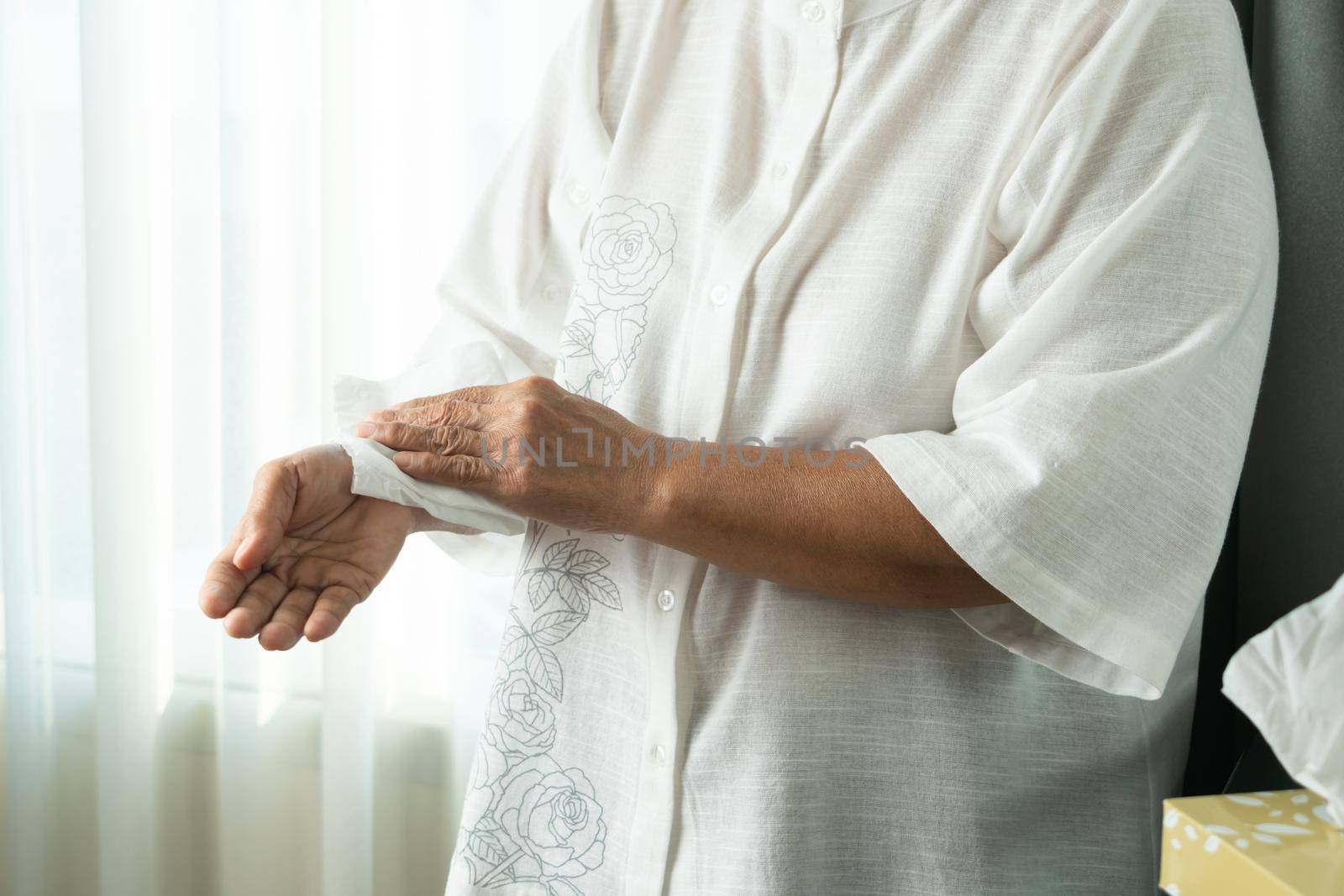 Senior woman cleaning her hands with white soft tissue paper. isolated on a white backgrounds by psodaz