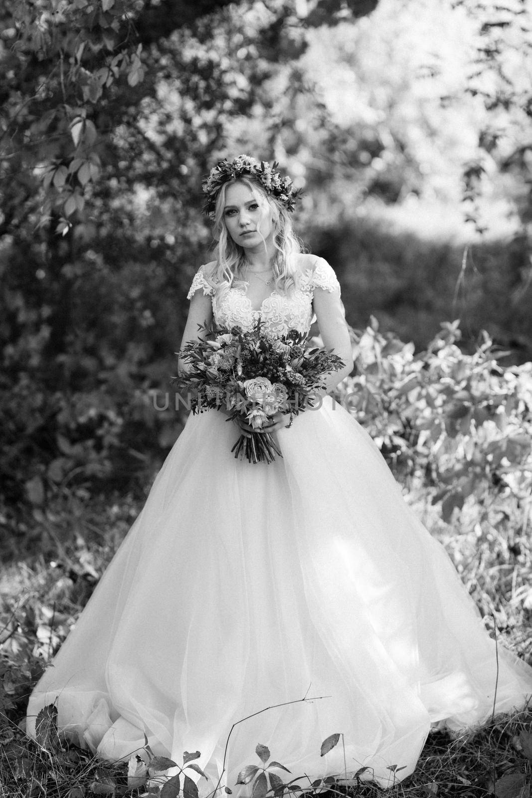 blonde girl in a wedding dress in the autumn forest against the background of wild red grapes