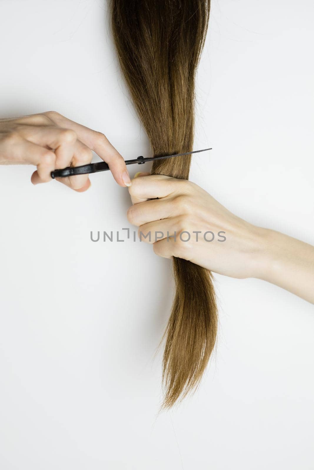 Upset woman cuts her long straight hair with scissors by Gleaminvisible