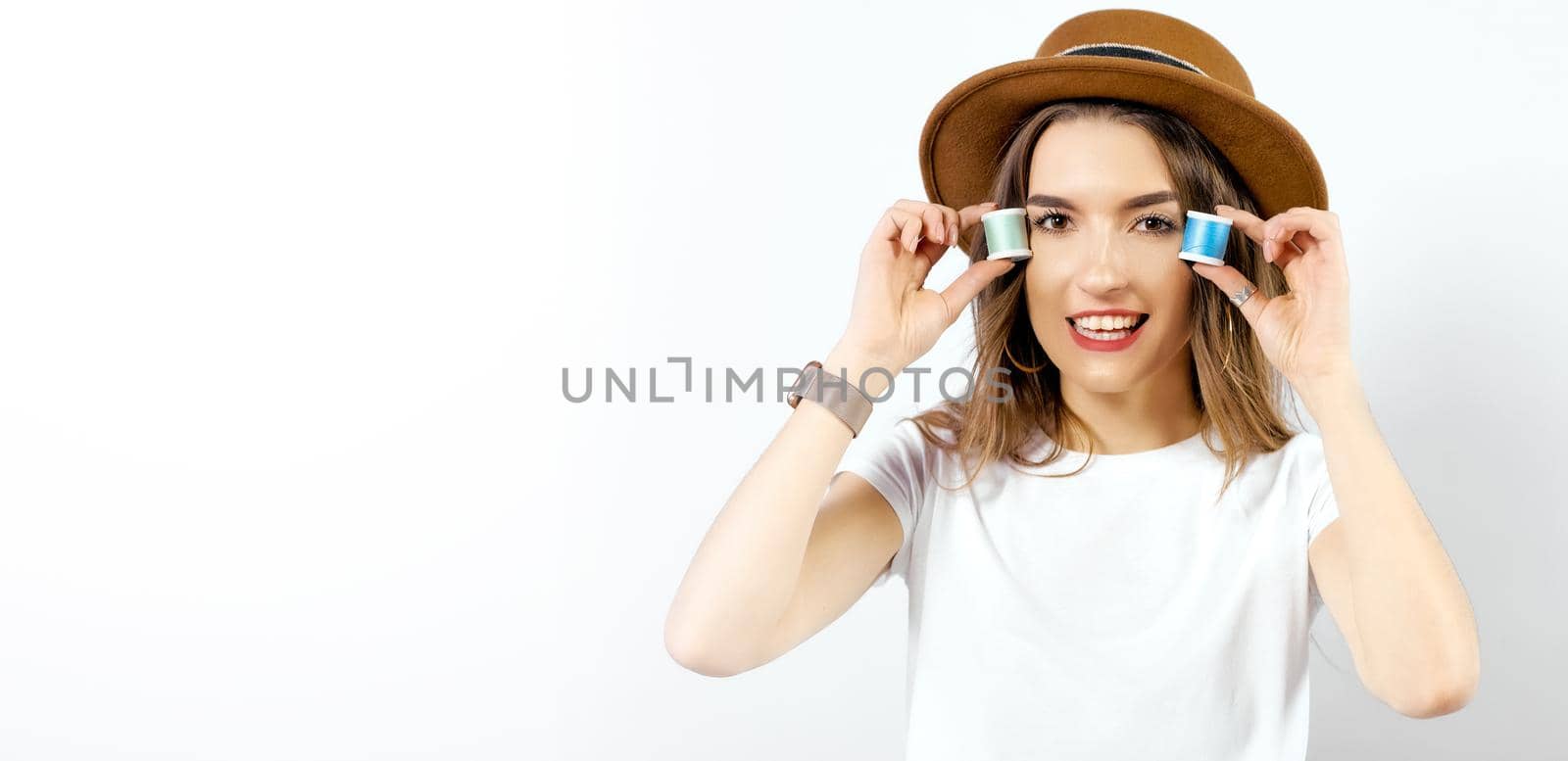 Happy girl in hat with coils of threads near eyes. High quality photo