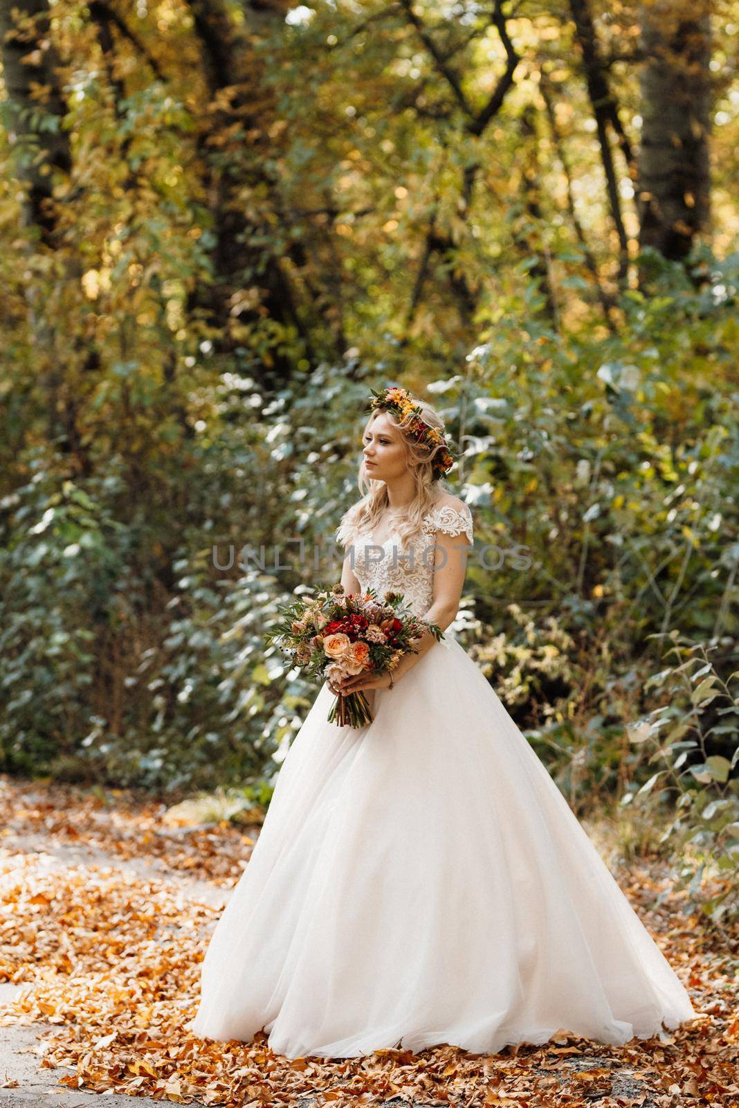 blonde girl in a wedding dress in the autumn forest