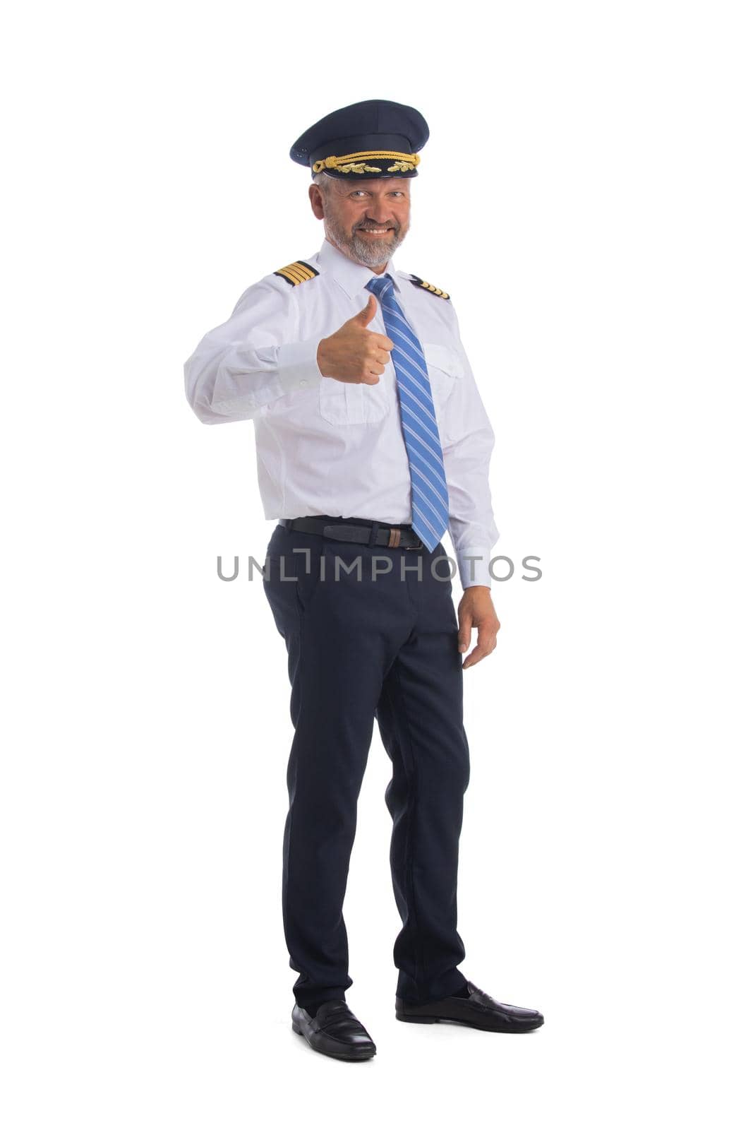 Cheerful airline pilot wearing uniform with epaulets showing thumb up gesture of approval, standing isolated on white background.