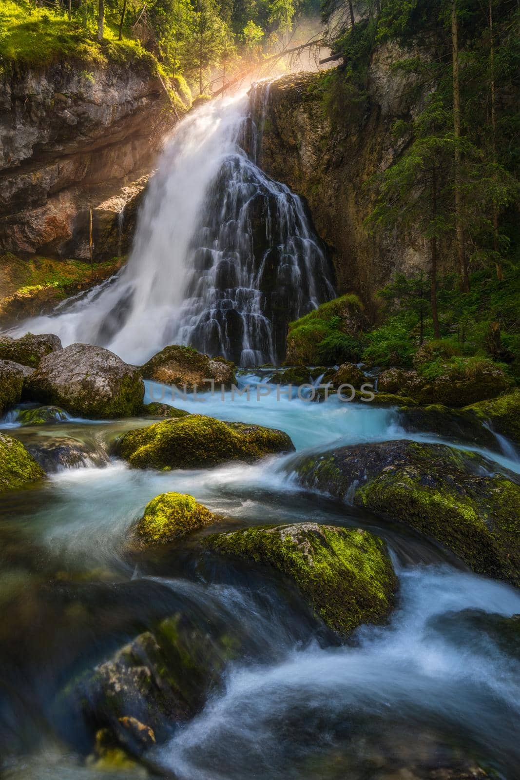 Gollinger Waterfall in Golling an der Salzach near Salzburg, Austria. Gollinger Wasserfall with mossy rocks and green trees, Golling, Salzburger Land, Austria.