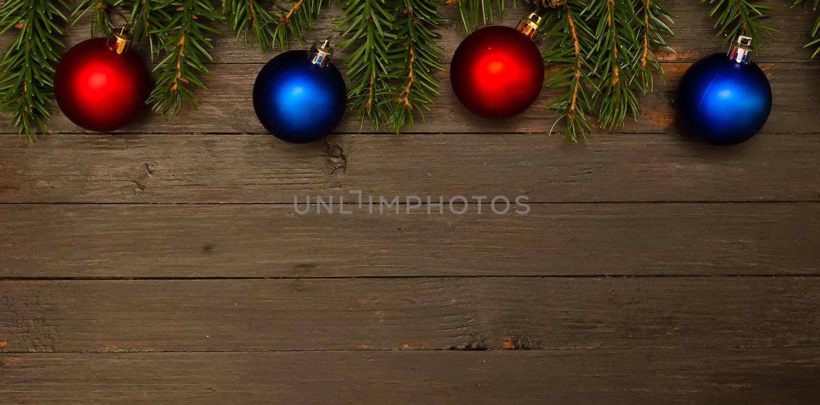 Christmas background.Two red christmas balls,two blue balls and fir tree branches on wooden background.