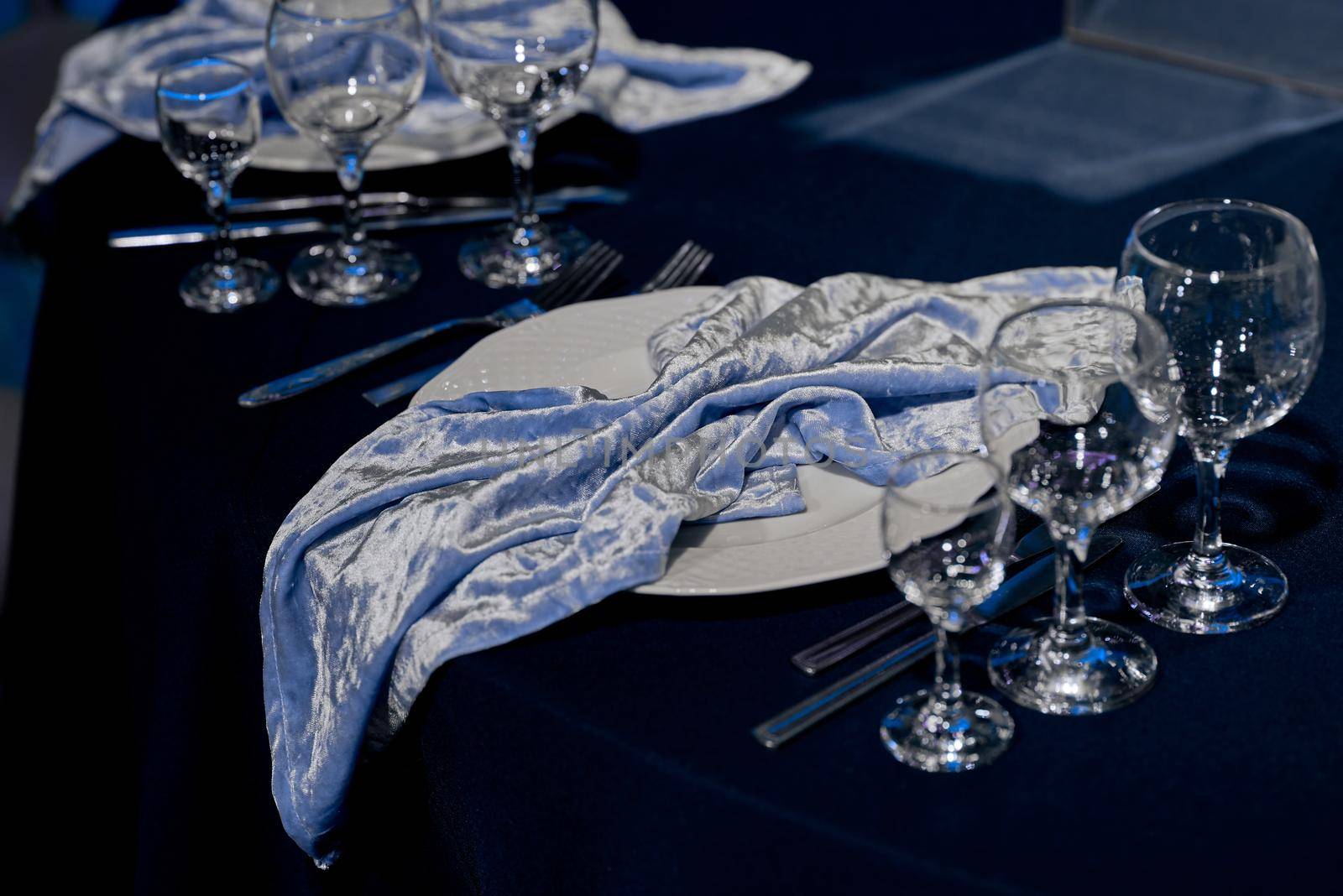 Served table with empty drinks glasses and a stylish blue napkin. In blue. by AntonIlchanka