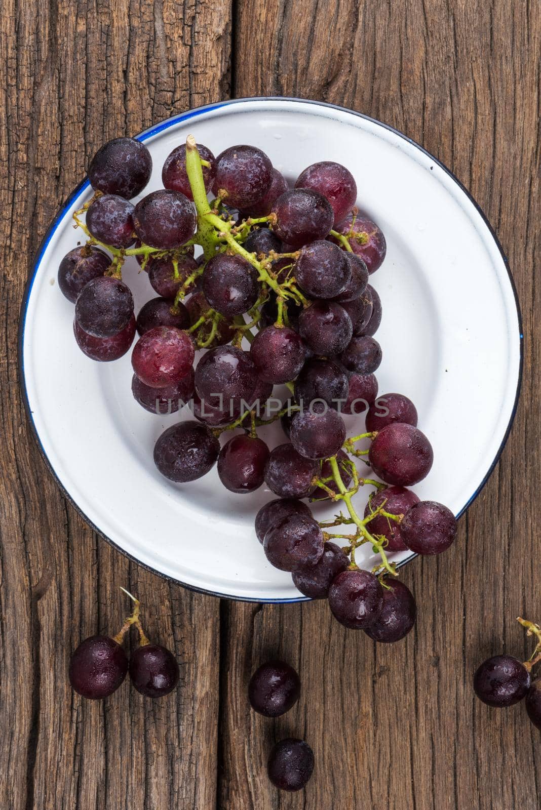isolate bunch of fresh red grapes on wooden plank