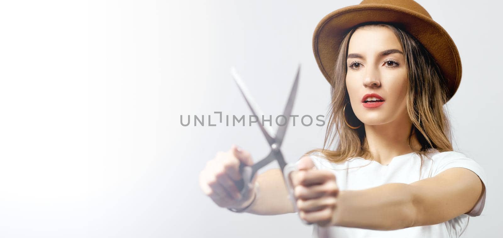 A woman wearing a hat looking through scissors hight quality 