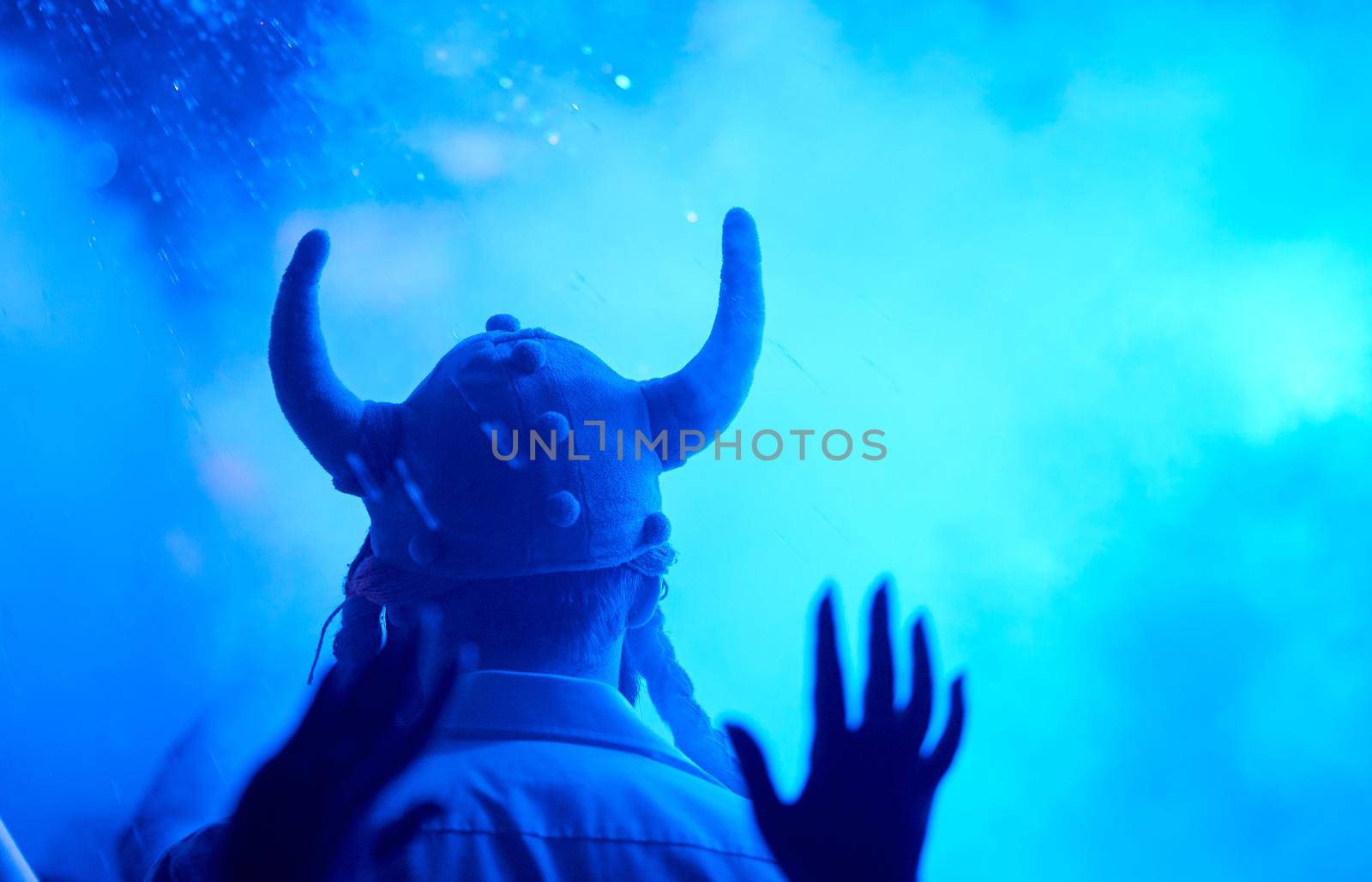 a pleased tall man backs in a cap with horns in the smoke from co2. High quality photo